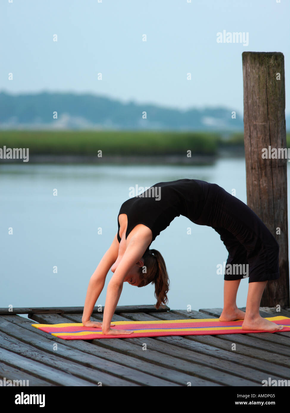 Woman doing yoga bridge position early morning on dock Virginia Beach VA Stock Photo