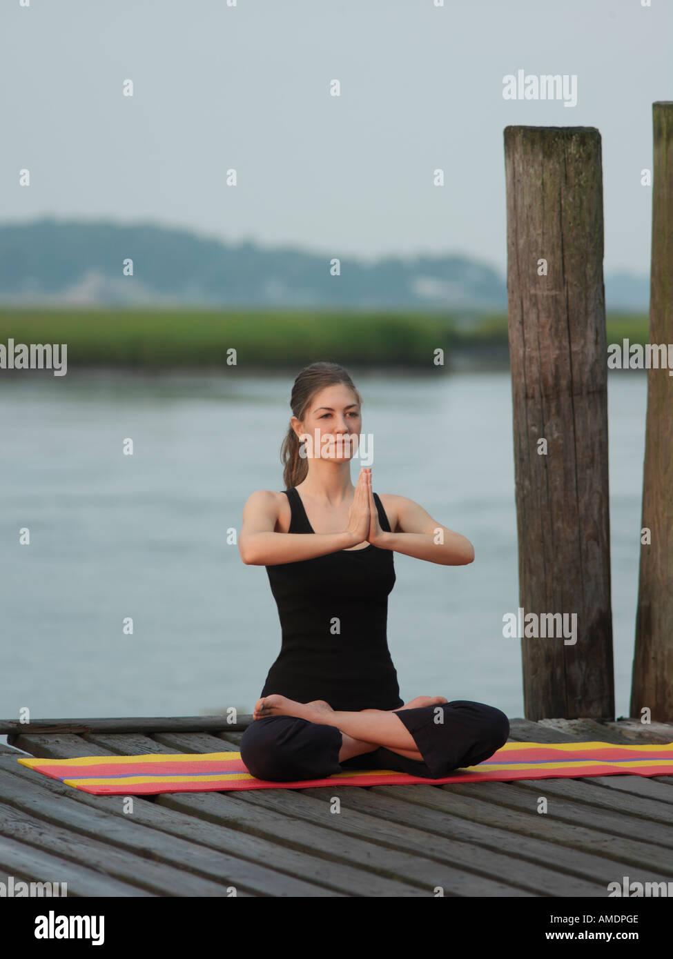 Woman doing yoga lotus position early morning on dock Virginia Beach VA Stock Photo