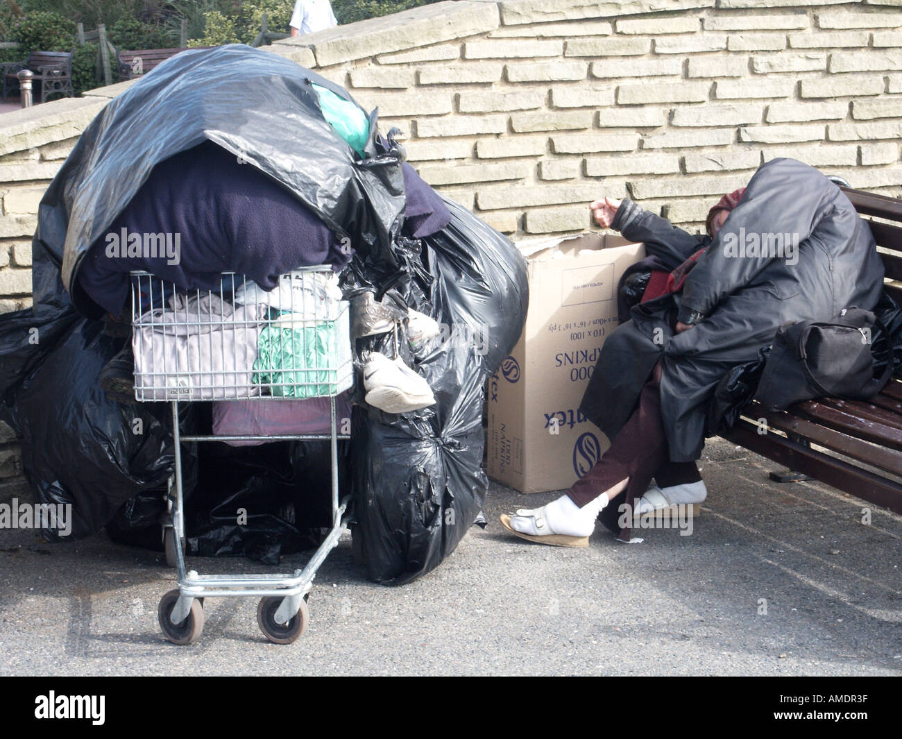 Worthing person sleeping rough on seafront promenade belongings in a supermarket trolley covered in bin bag plastic Stock Photo