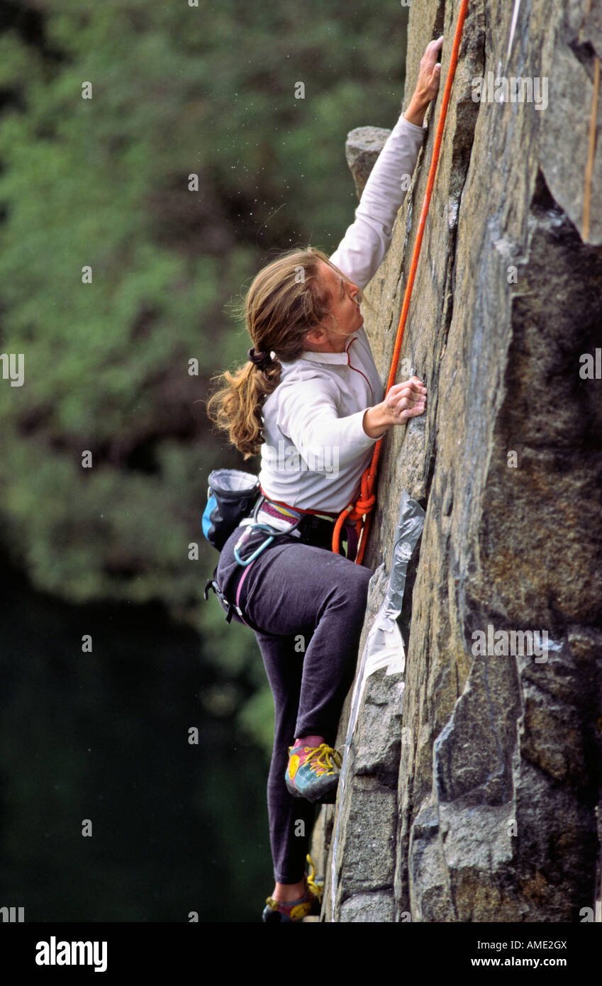 Woman rock climber scales a wall in an abandonded quarry in Quincy Massachusetts Stock Photo