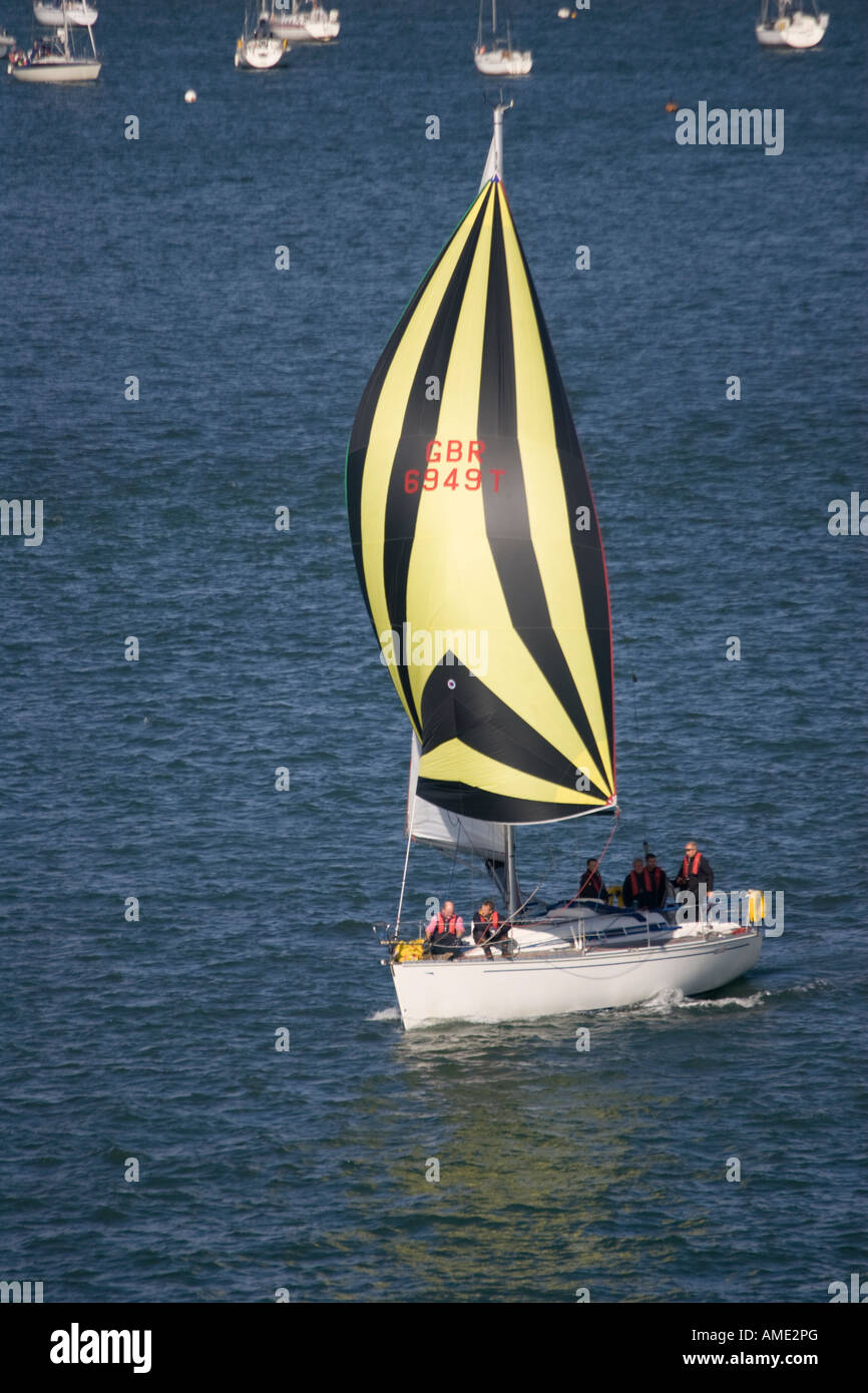 Sailing yacht with spinnaker sailing out of Poole Harbour Dorset UK