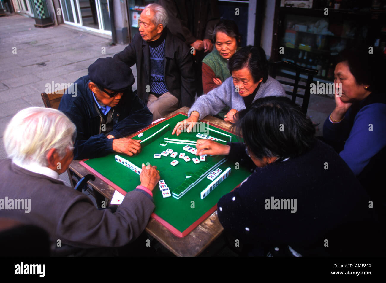 Four Chinese pensioners gather around a mahjong table, engaging in a ...
