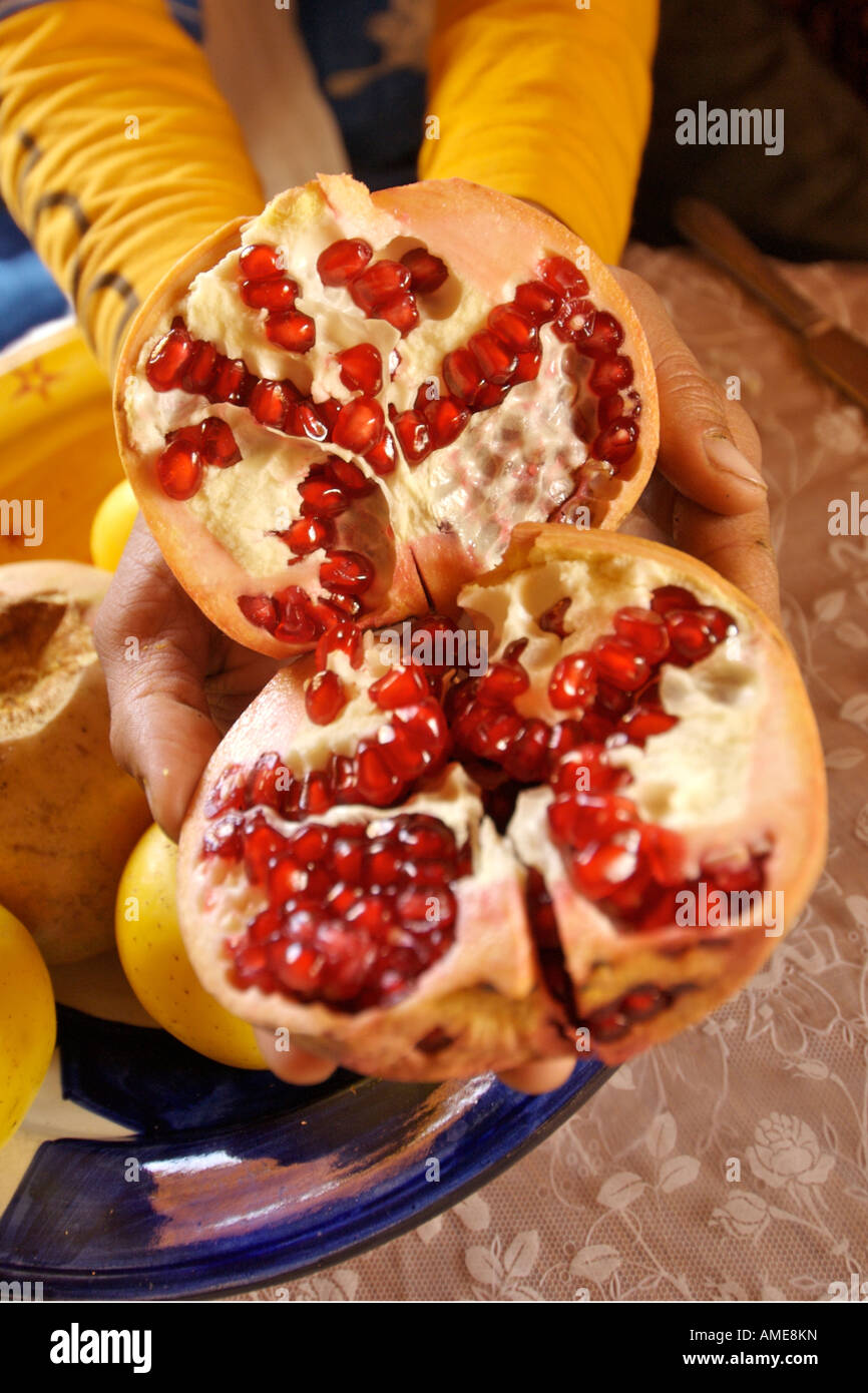 A berber man holds an open pomegranate displaying the edible red berries inside. Stock Photo