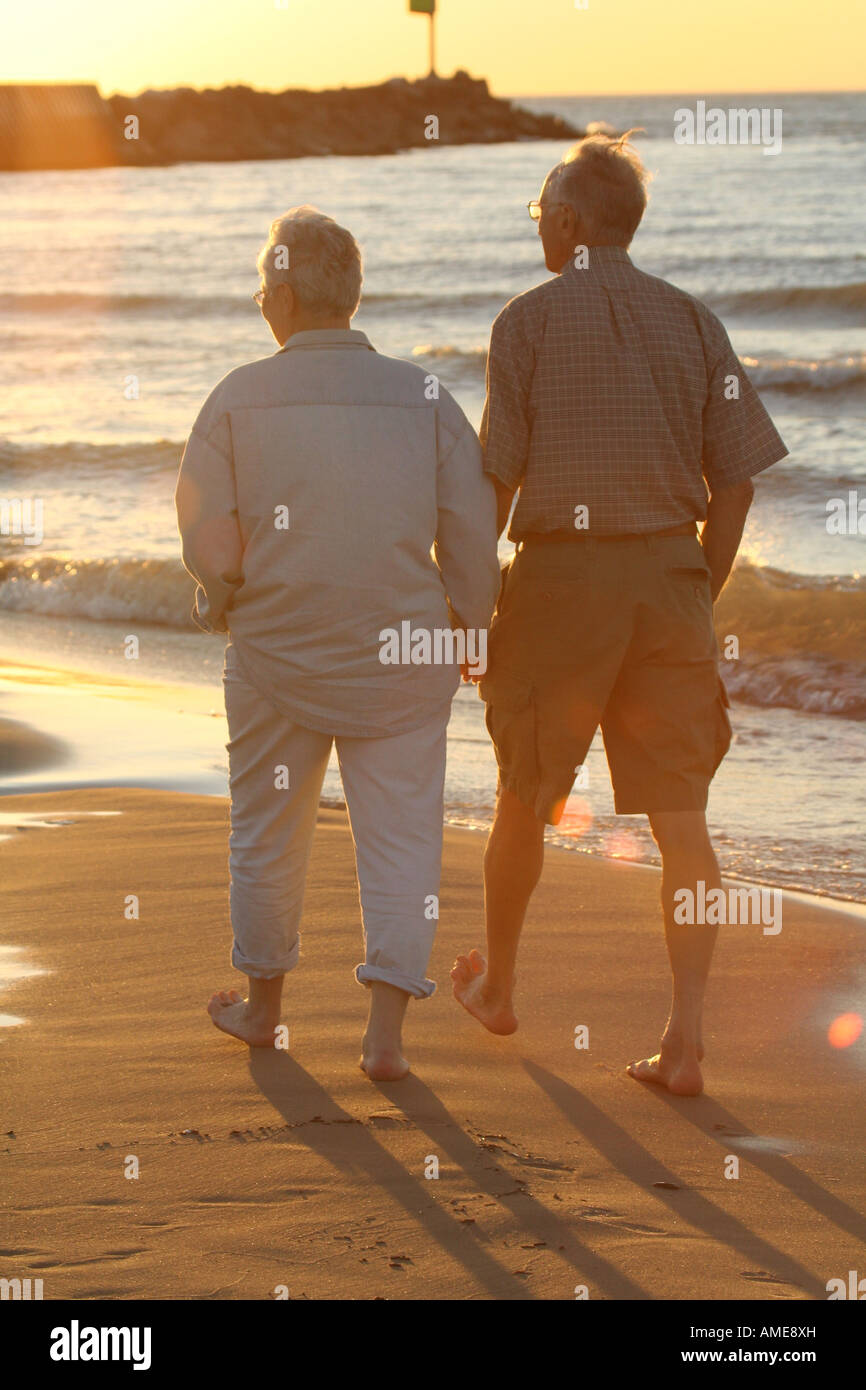 Older couple holding hands walking on beach Stock Photo - Alamy