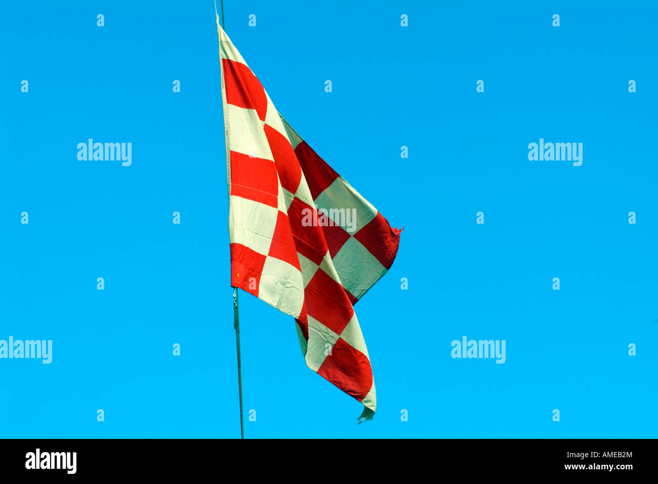 Red And White Checkered Flag Flying Against A Blue Sky Stock Photo