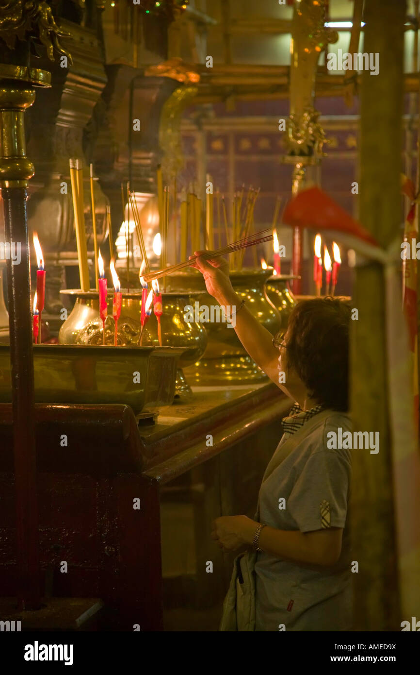 A woman burns incense sticks in the Man Mo temple, Hollywood Road, Hong Kong Stock Photo