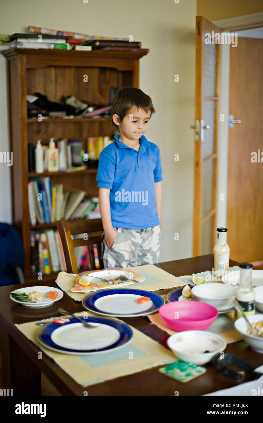 Boy looks at dining table with empty plates after lunch Stock Photo