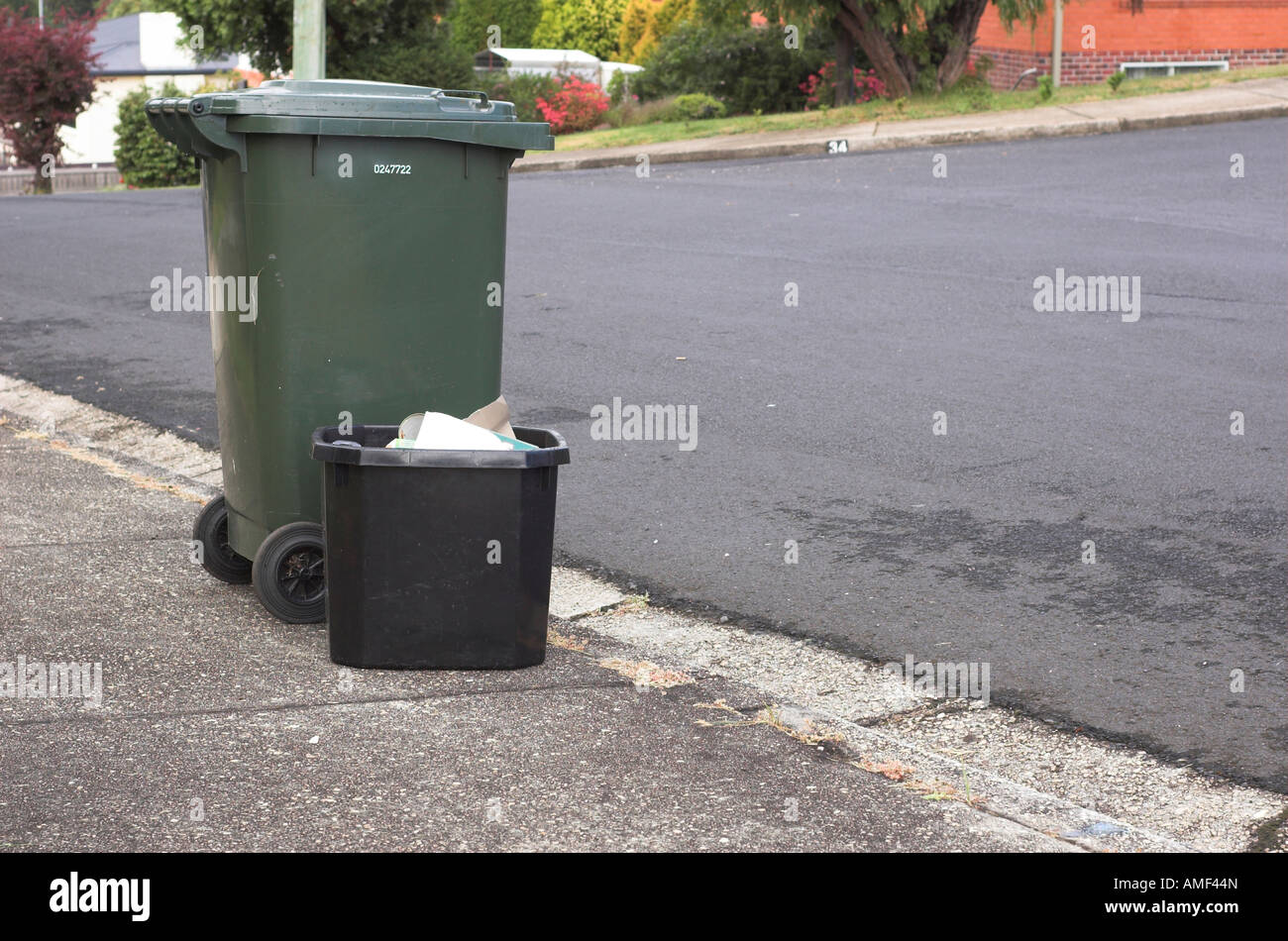 A wheelie bin and black recycling box out on the pavement on bin day