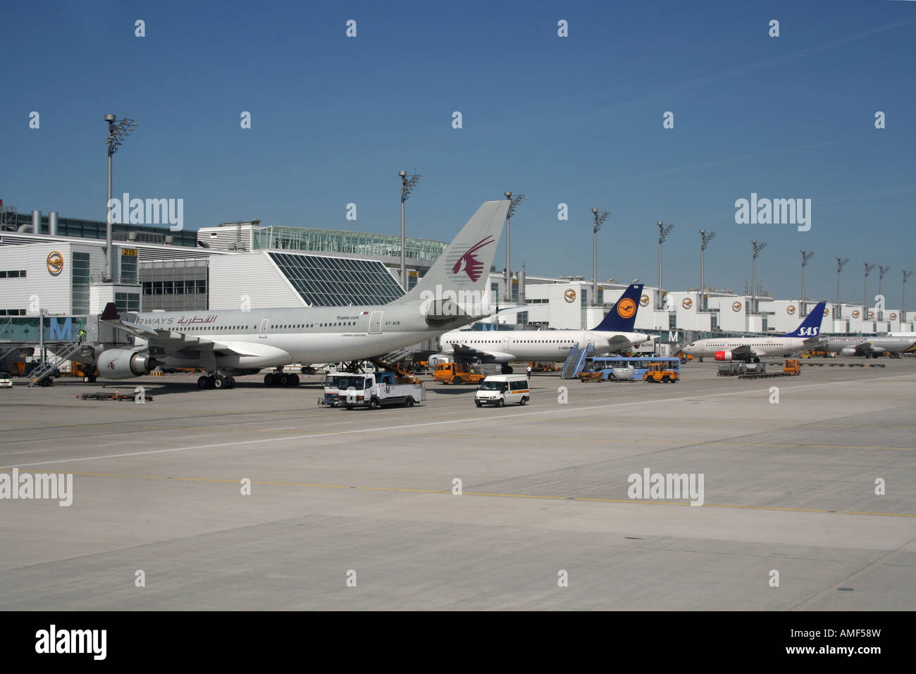 Airport and planes. Aircraft at their gates at Munich Airport, Germany. A Qatar Airways Airbus A330 is in the foreground. Air travel. Stock Photo