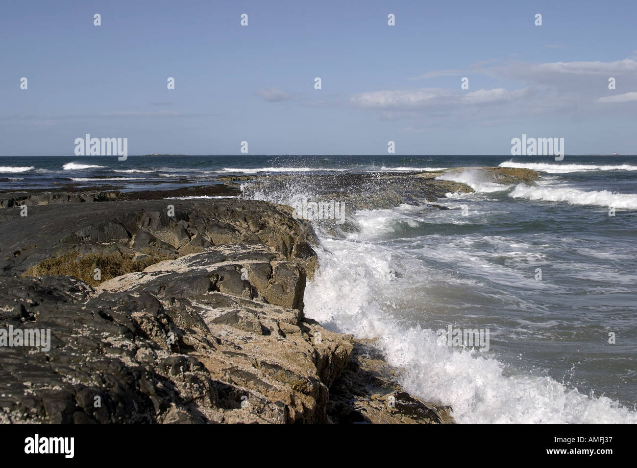 landscape shot of tide coming in against rocks with barnacles attached ...