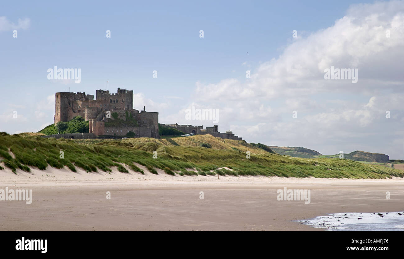landscape shot of Bamburgh castle as taken from the beach showing sand sea and sky Stock Photo
