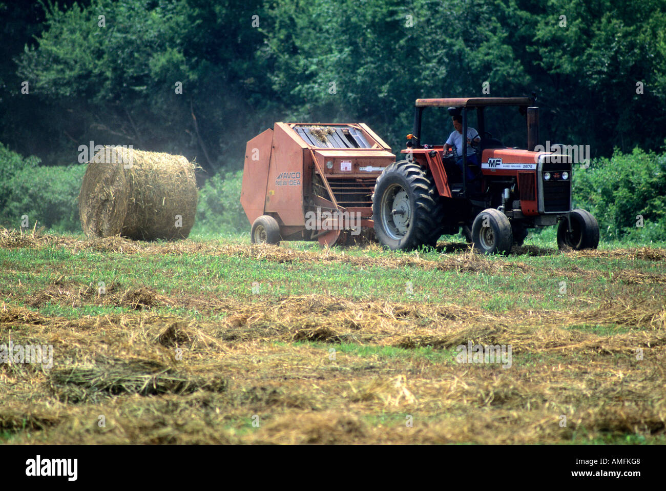 A tractor pulling a round hay baler. Stock Photo