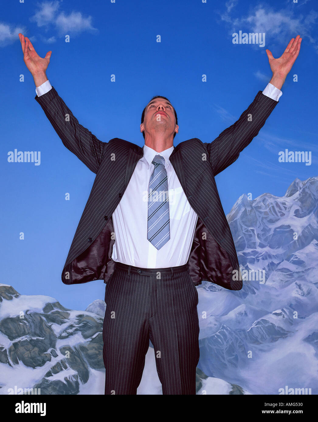 A portrait of a young businessman with arms outstretched against a mountain top background Stock Photo