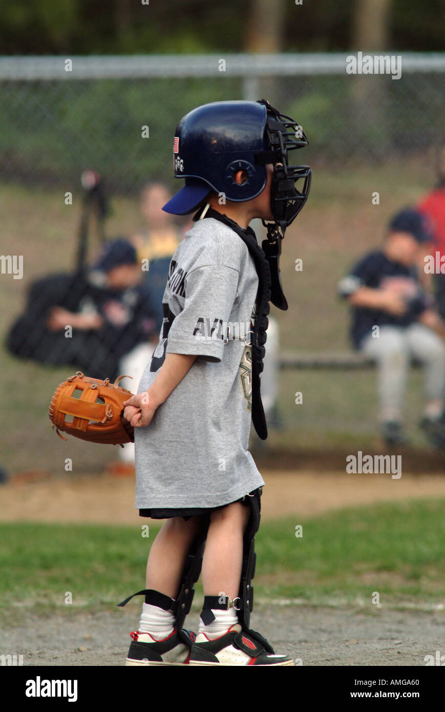 The catcher at a T ball game intently grips the baseball 5 year old boy