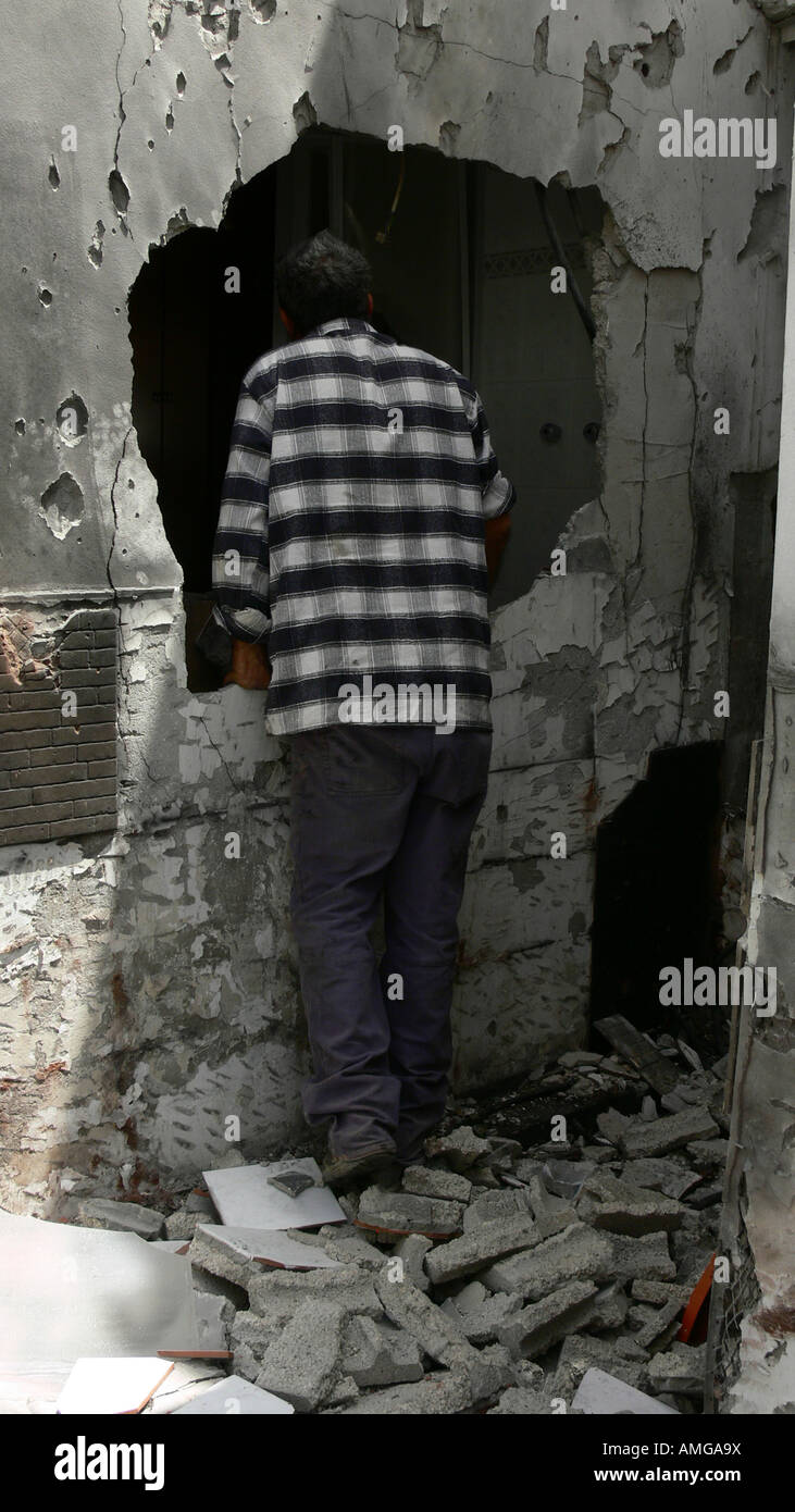 Israel Sderot house damaged by a Qassam rockets launched by Hamas from Gaza Man inspecting the damage to his home Stock Photo