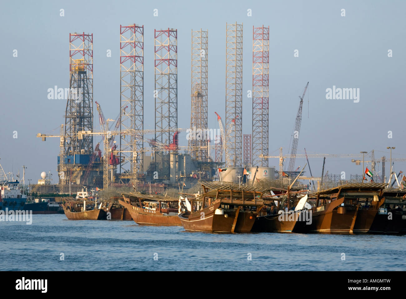 Jack-up oil gas rig & harbour, docks and Arab dhows at Al Sharjah - Khalid Port of Sharjah at the creek, UAE United Arab Emirates Stock Photo