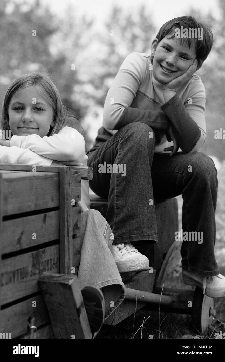 Portrait of Two Girls Sitting On Soapbox Car Outdoors Stock Photo