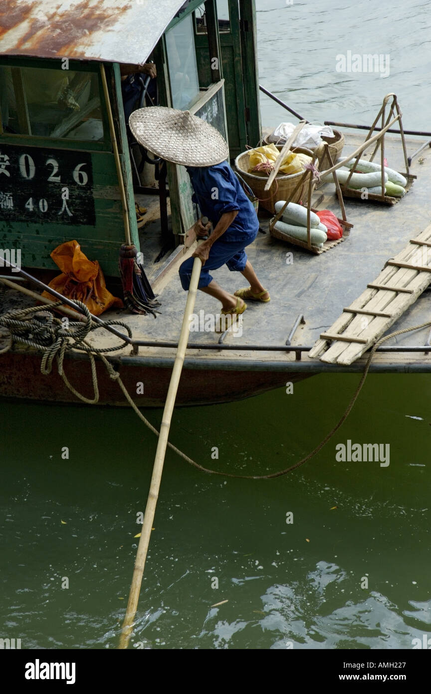 China Guangxi Fuli Village Near Yangshuo A Man Pushing The Passengers Boat Away From The Banks With Oars On Li Jiang River Stock Photo