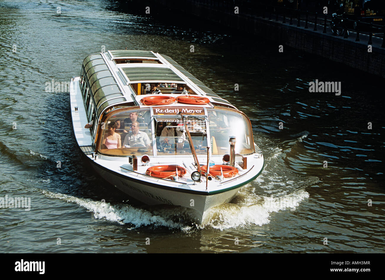 White canal tourist boat travelling on a canal, Amsterdam, Holland Stock Photo