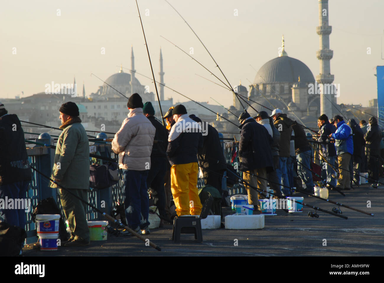 ISTANBUL Line fishing on the Golden Horn from the Galata Bridge, with the Yeni ('New') Mosque behind. 2007. Stock Photo