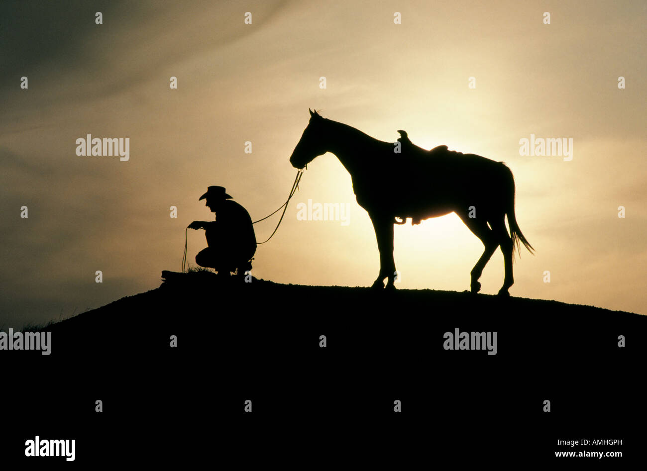 A cowboy and his horse at sunset on a large cattle ranch near Post Texas in the Texas panhandle Stock Photo
