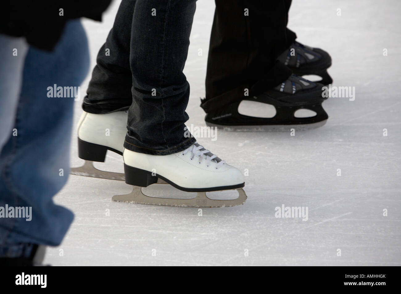 legs and feet of people ice skating on an outdoor rink for christmas