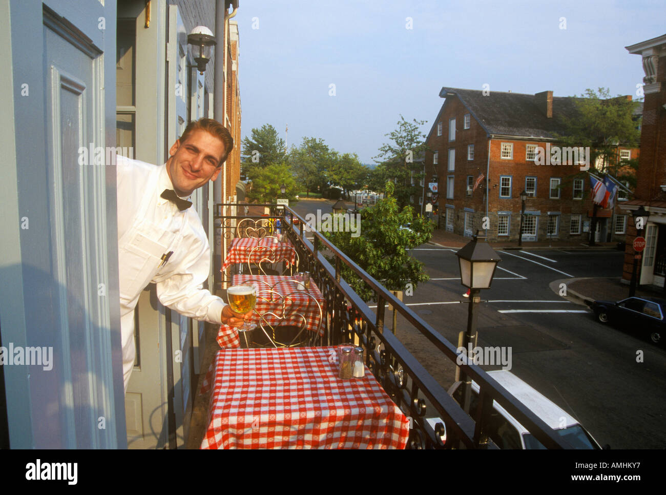 Male waiter outside red checked tables at outdoor Fish Market restaurant in Alexandria VA Stock Photo