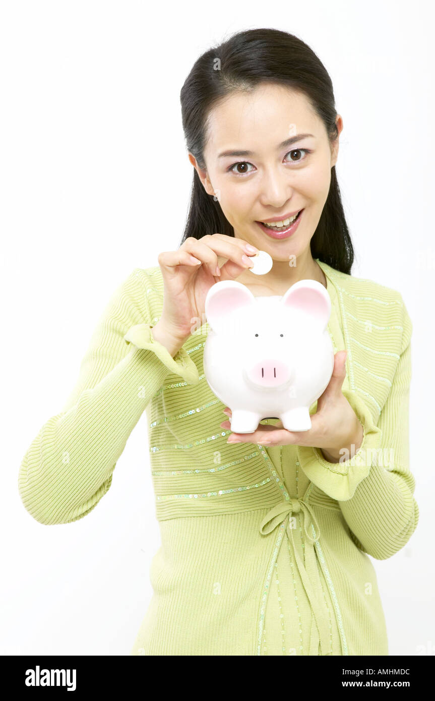A woman putting a coin into the piggy bank on her hand Stock Photo - Alamy