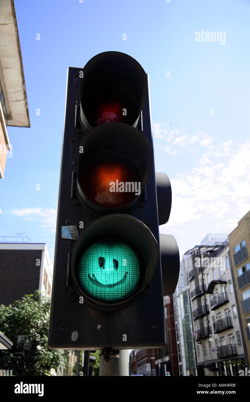 Traffic light on green with smiley face drawn on it. Old Street, Hackney,  London, England Stock Photo