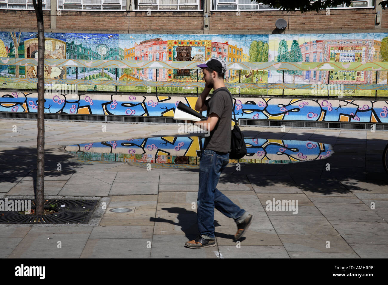 Man on mobile phone walking past mural. Old Street, Hackney, London, England Stock Photo