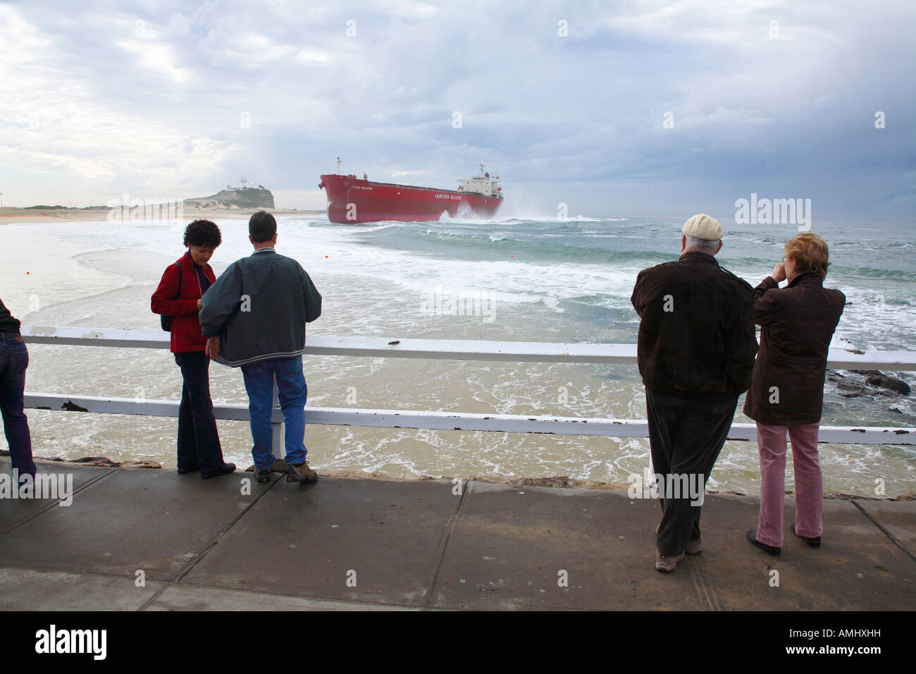 People on a pier watching a large red ship shipwrecked Newcastle NSW Australia Stock Photo