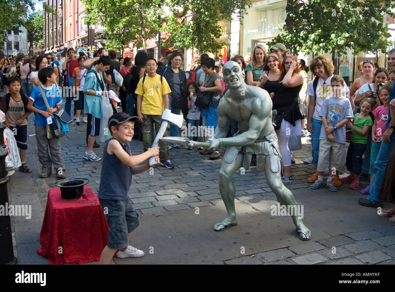Mime artist Duncan Meadows as a human statue play fighting with child at Covent Garden London
