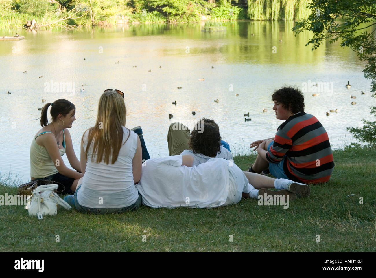 Group of teenagers socialising beside a pond on Hampstead Heath, London, UK Stock Photo