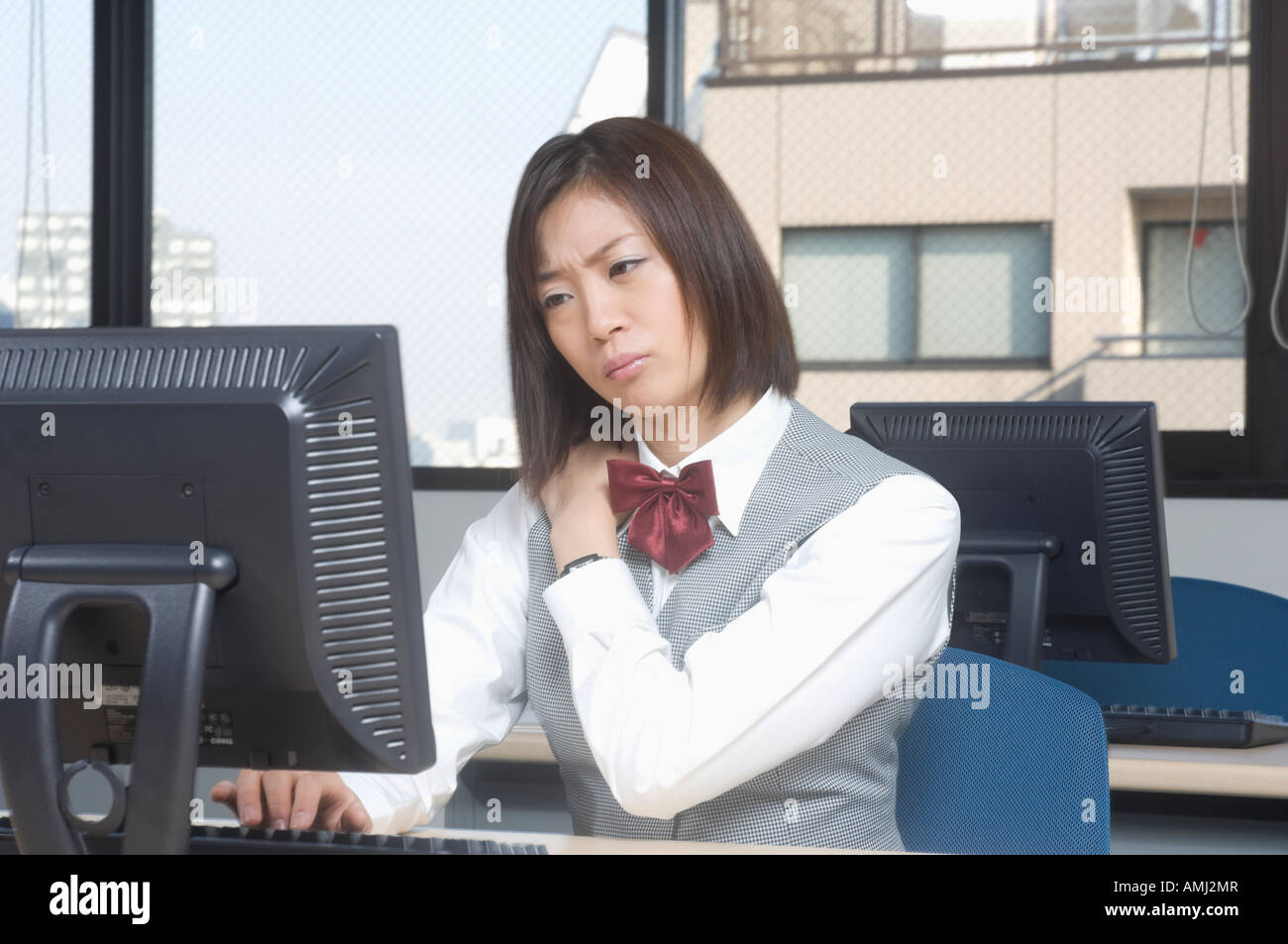 Office worker rubbing her neck Stock Photo - Alamy