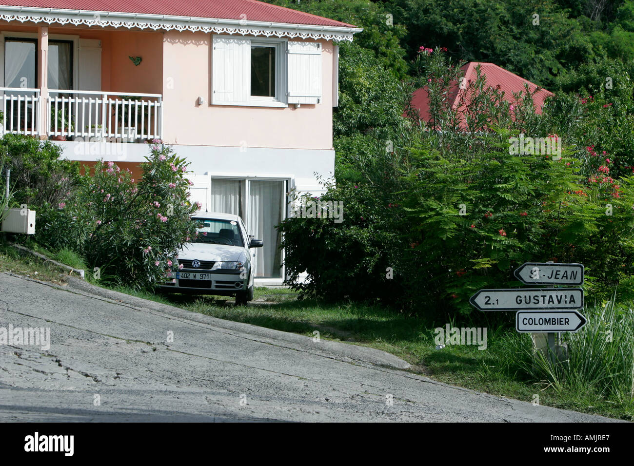 Pink pastel private house with balcony on steep narrow lane with road signs St Barts Stock Photo