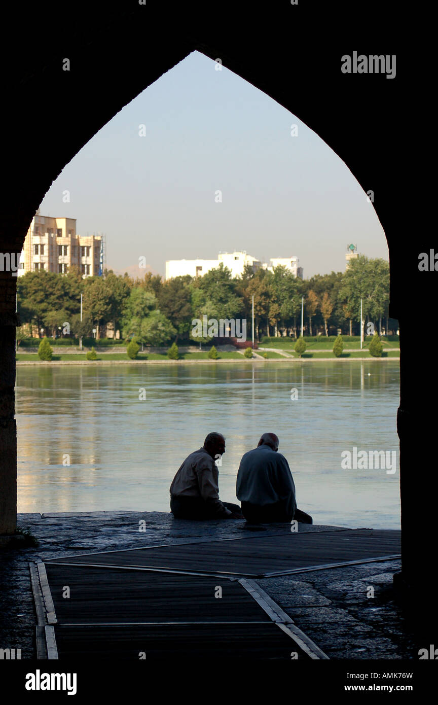 Friends sitting under arch on Khaju Bridge in Isfahan, Iran Stock Photo