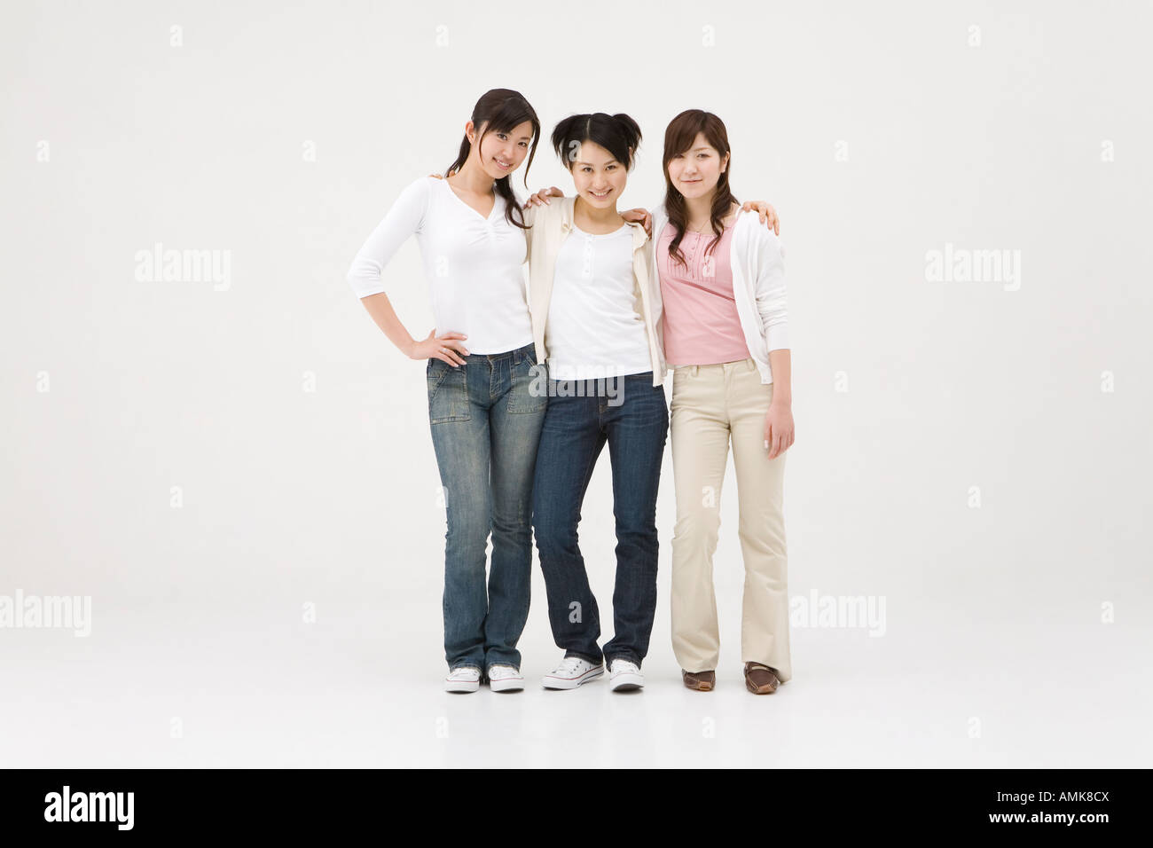 Three young women standing with arms around Stock Photo