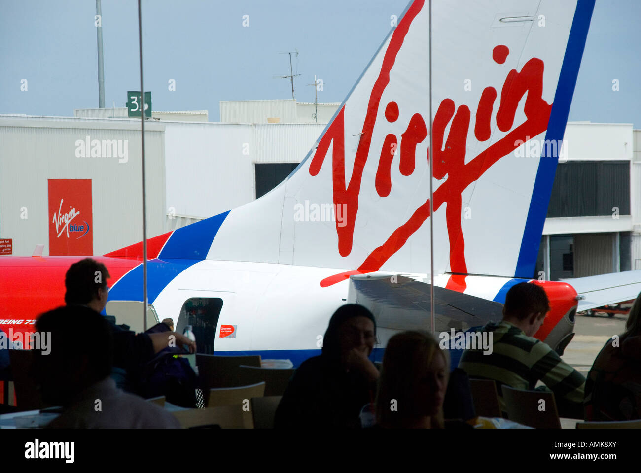 Passengers waiting for boarding call at domestic airport in Australia looking out to a Virgin airlines aircraft Stock Photo