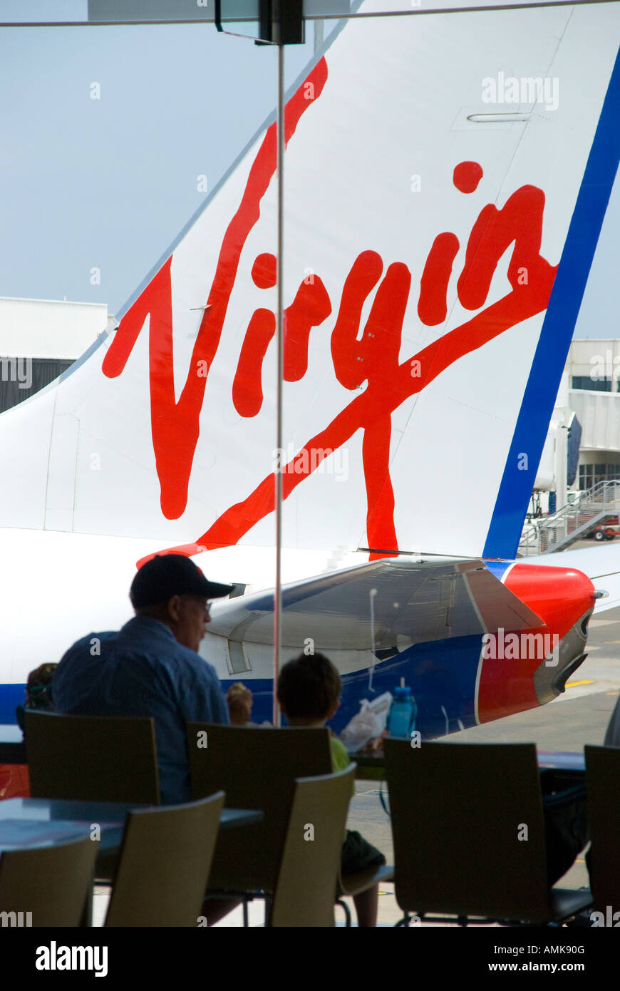 Passengers waiting for boarding call at domestic airport in Australia looking out to a Virgin airlines aircraft Stock Photo