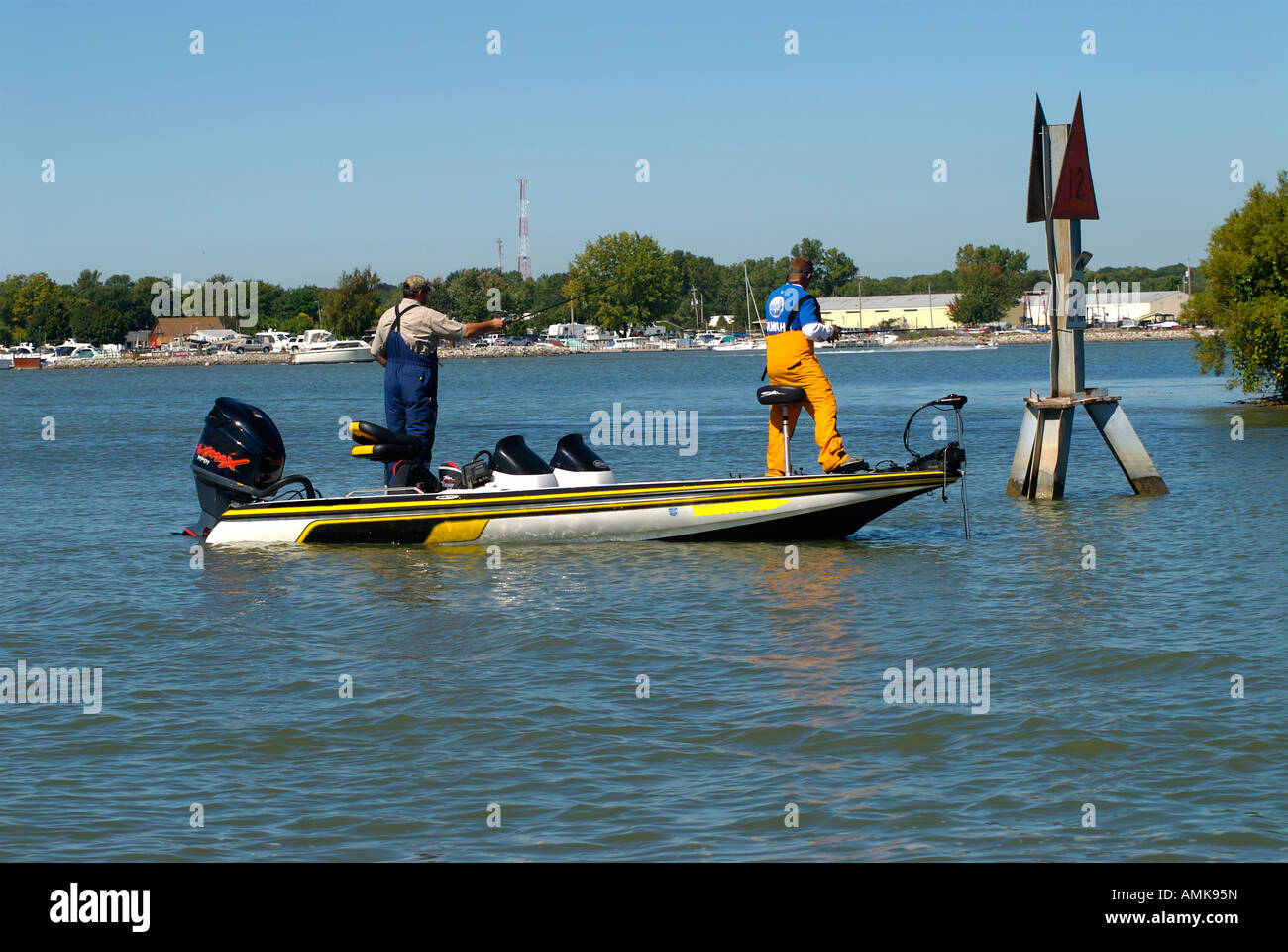 two fishermen in bass boat fishing in shallow waters near navigation marker Stock Photo