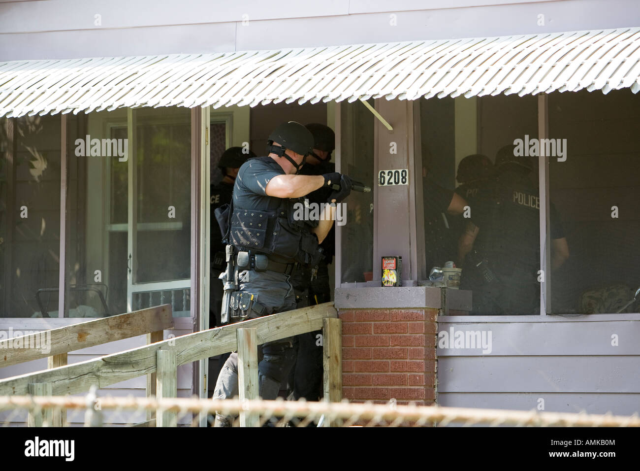 Police officers from tactical narcotics unit carrying out high risk search warrant in suspected drug house. Kansas City SWAT. Stock Photo