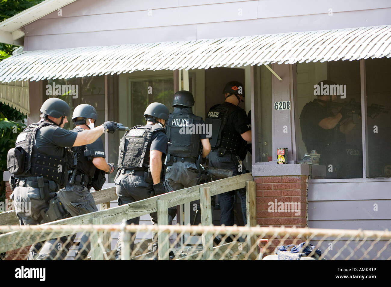 Police officers from tactical narcotics unit carrying out high risk search warrant in suspected drug house. Kansas City SWAT. Stock Photo