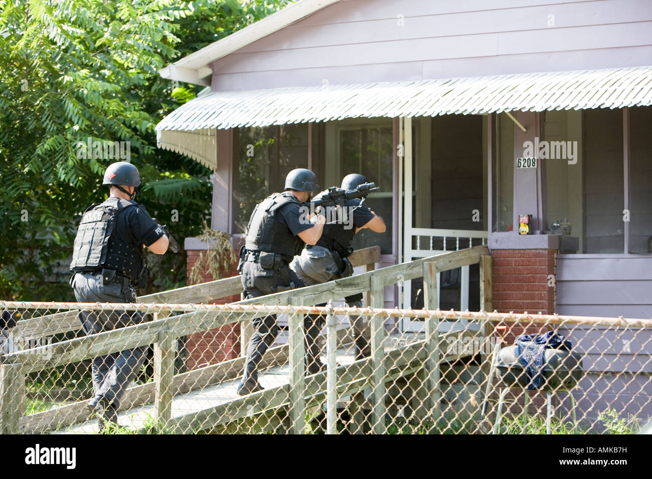 Police officers from tactical narcotics unit carrying out high risk search warrant in suspected drug house. Kansas City SWAT. Stock Photo