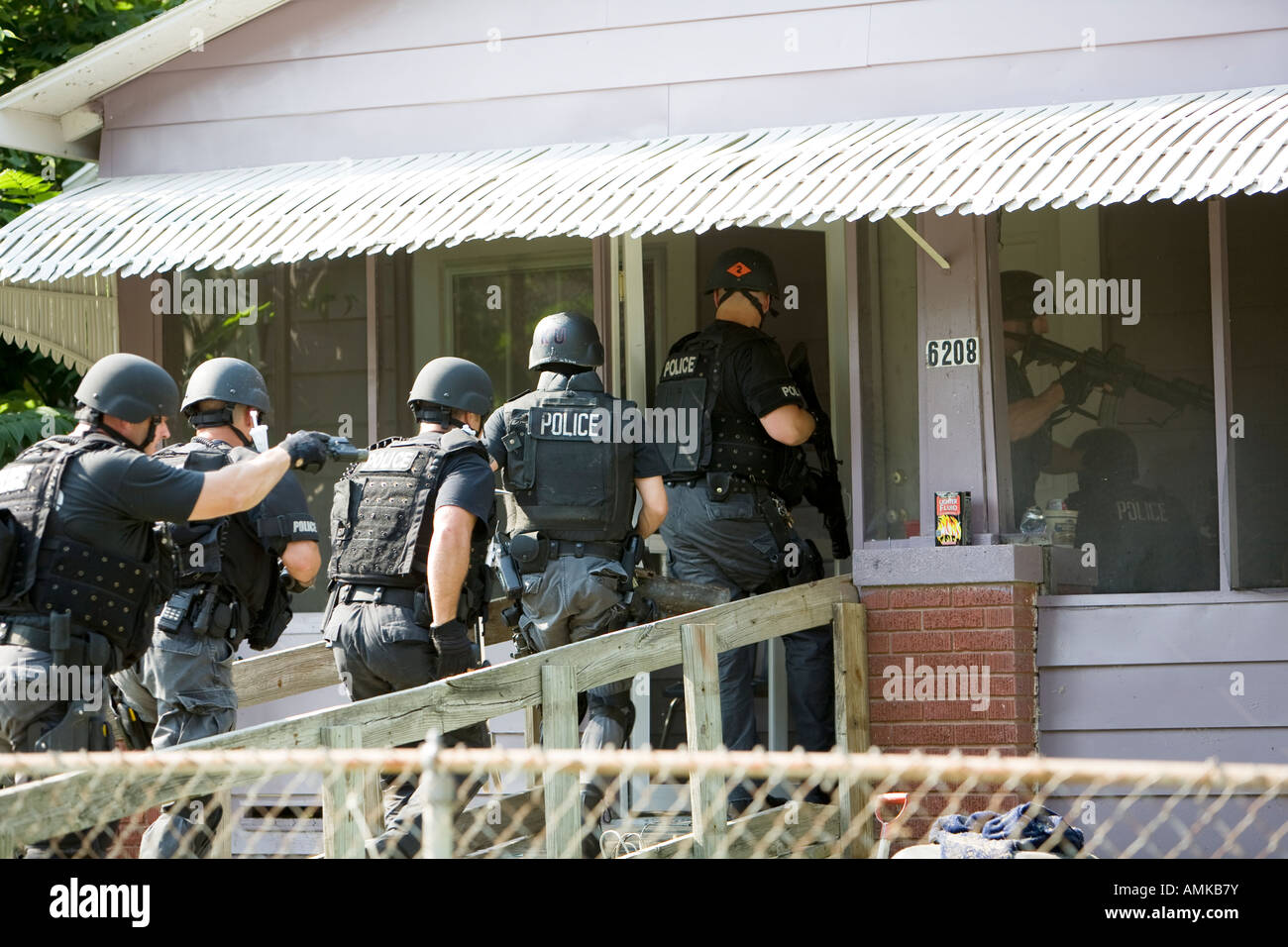 Police officers from tactical narcotics unit carrying out high risk search warrant in suspected drug house. Kansas City SWAT. Stock Photo