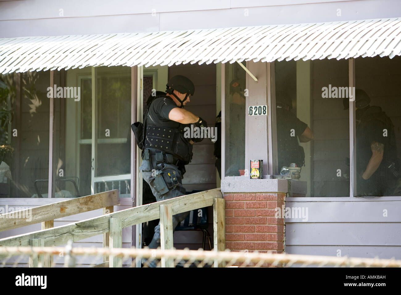 Police officers from tactical narcotics unit carrying out high risk search warrant in suspected drug house. Kansas City SWAT. Stock Photo