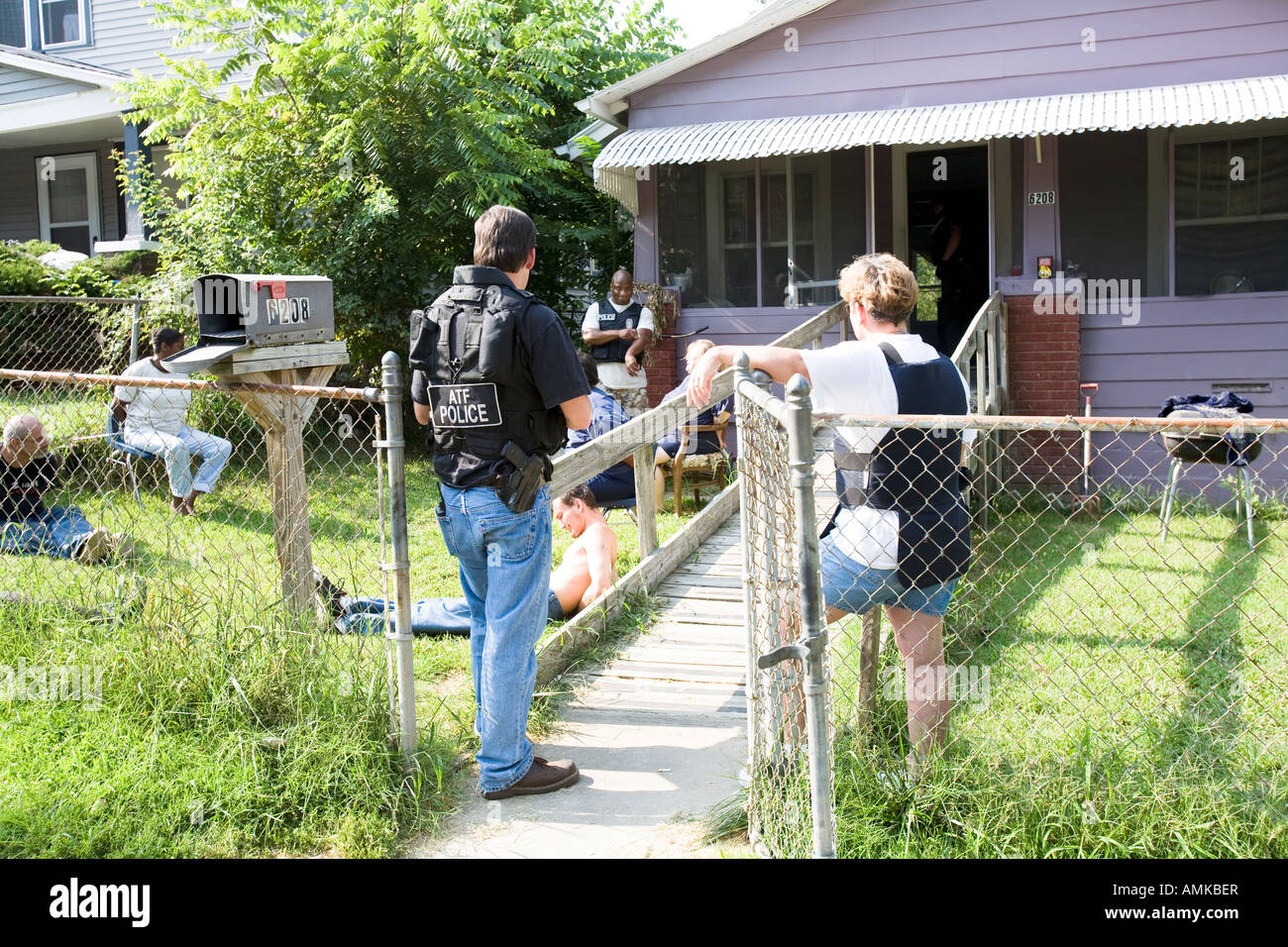 ATF agent and female police officer keeps watch over handcuffed female, narcotics raid. Kansas City, Missouri. Stock Photo