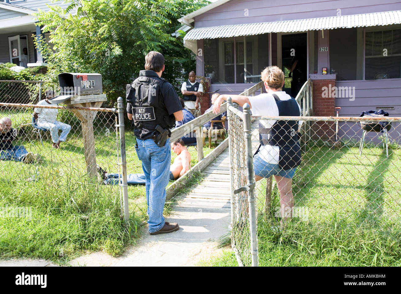 ATF agent and female police officer keeps watch over handcuffed female, narcotics raid. Kansas City, Missouri. Stock Photo