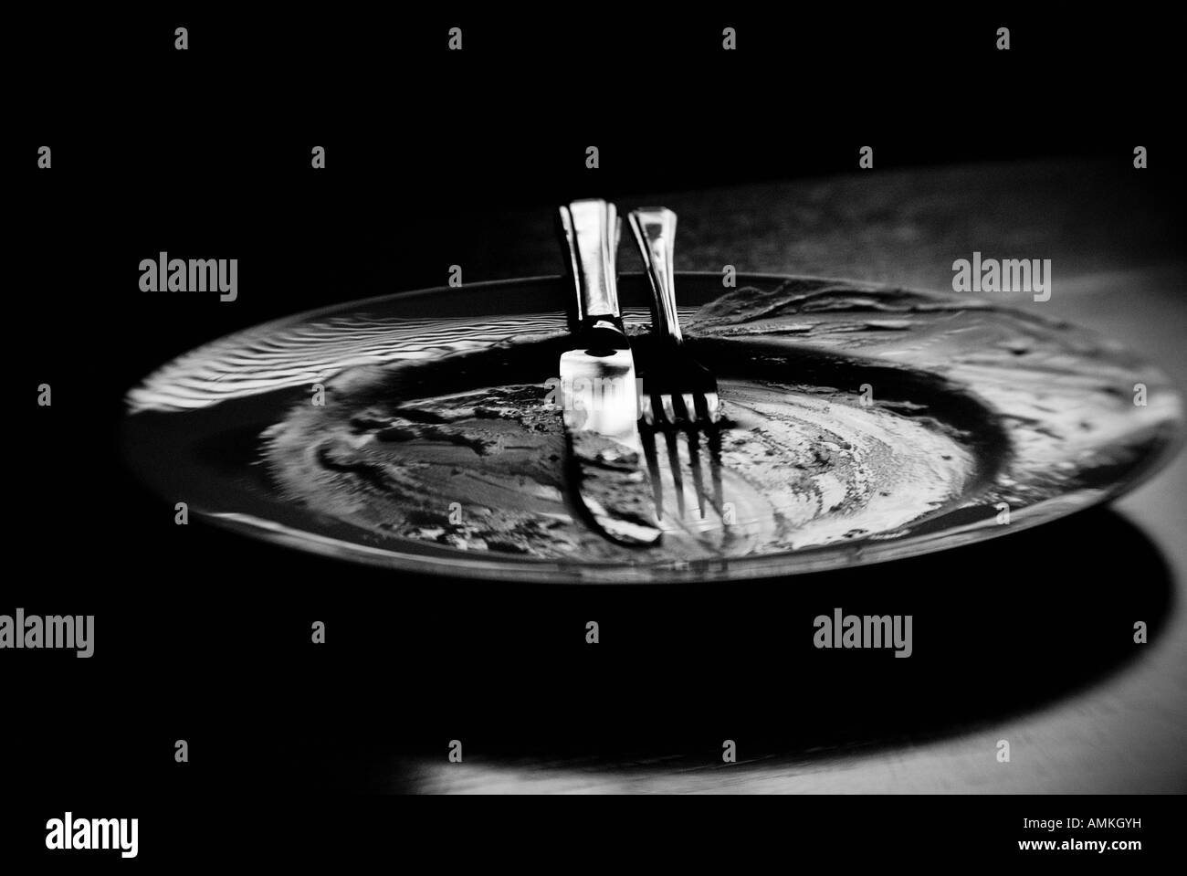 Black and white image of an empty dinner plate and cutlery Stock Photo