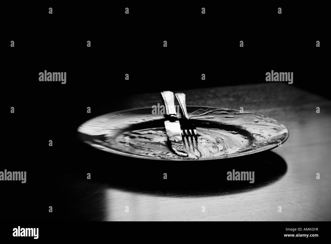 Black and white image of an empty dinner plate and cutlery Stock Photo