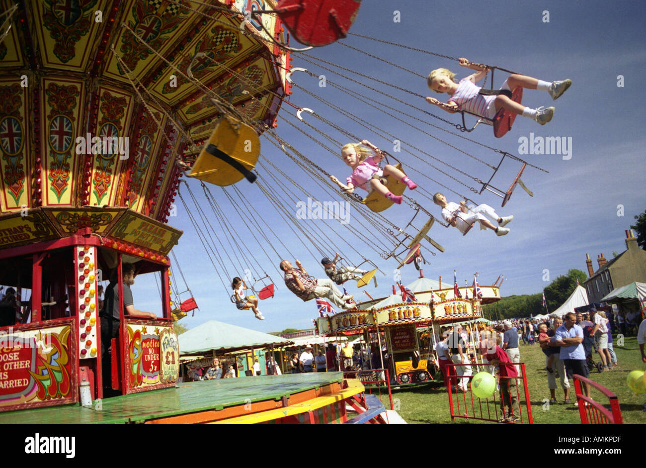 Two girls ride in seats on a carousel. Findon Village Sheep Fair, West Sussex England Stock Photo